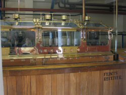 The sealed glass and brass box where all the distilled liquid passes through - every drop of Lagavulin goes through here.
